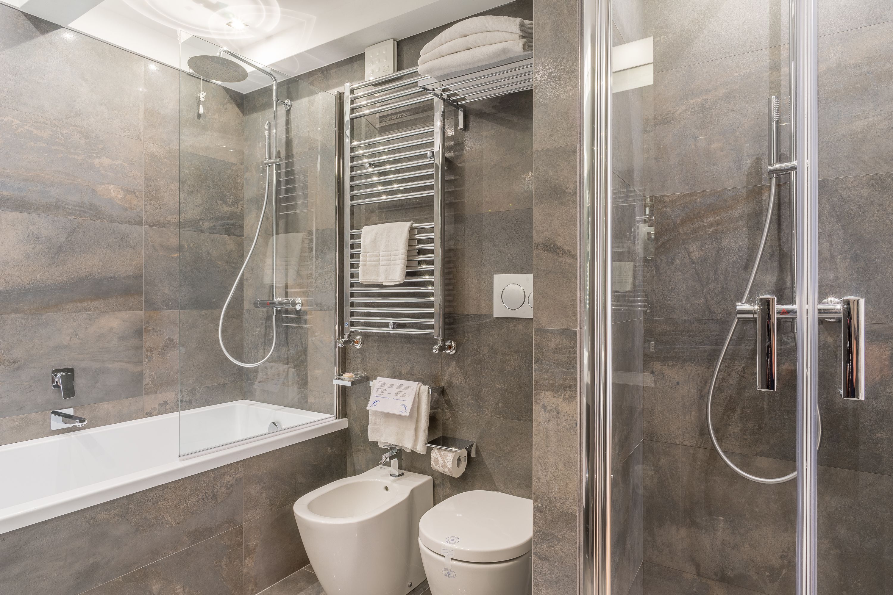A modern bathroom with a glass-enclosed shower, a standalone bathtub, and a toilet.