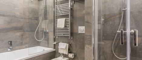 A modern bathroom with a glass-enclosed shower, a standalone bathtub, and a toilet.