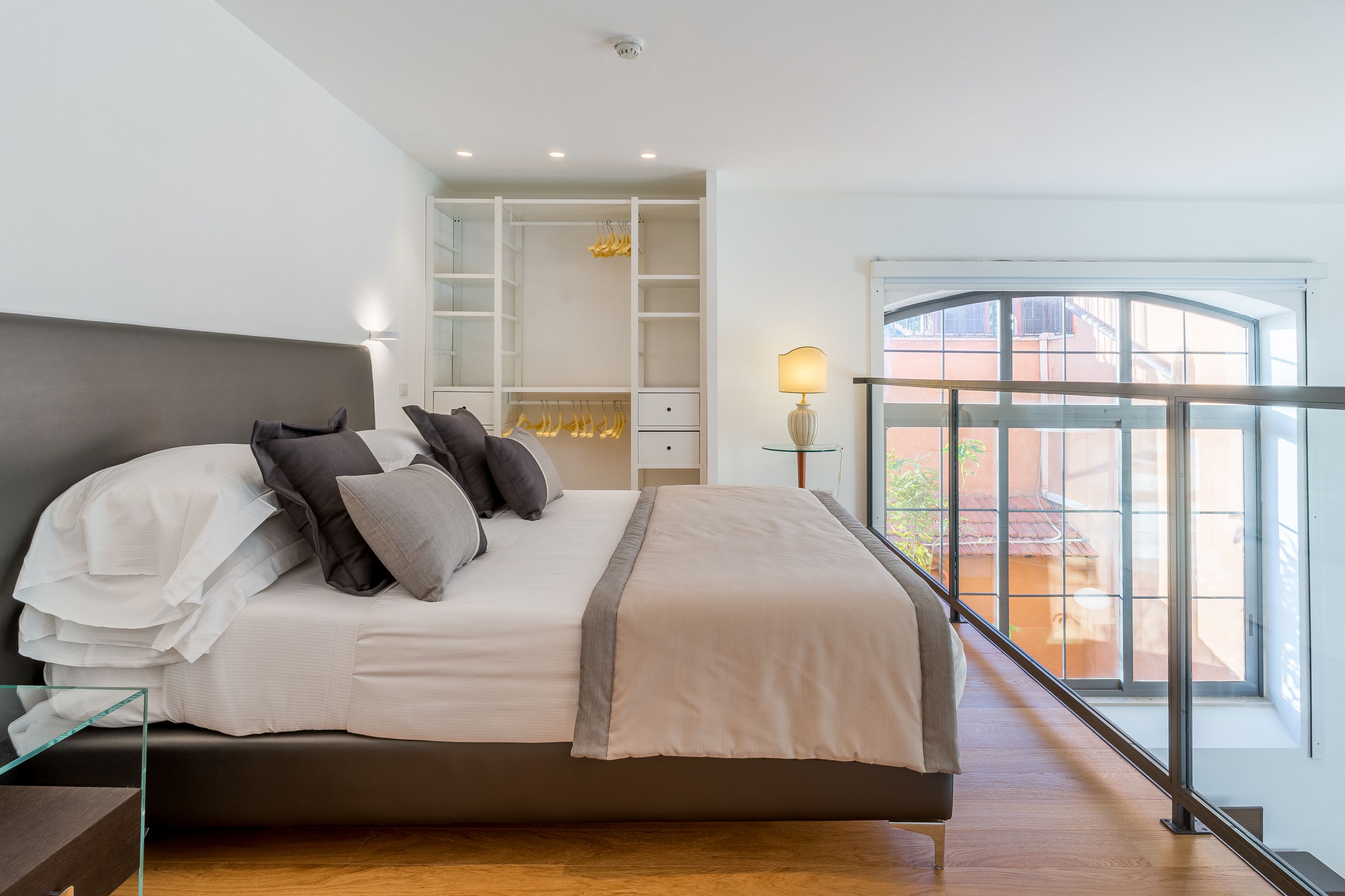 Un dormitorio moderno con una cama grande, armario empotrado y un balcón con vistas.