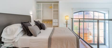 Un dormitorio moderno con una cama grande, armario empotrado y un balcón con vistas.