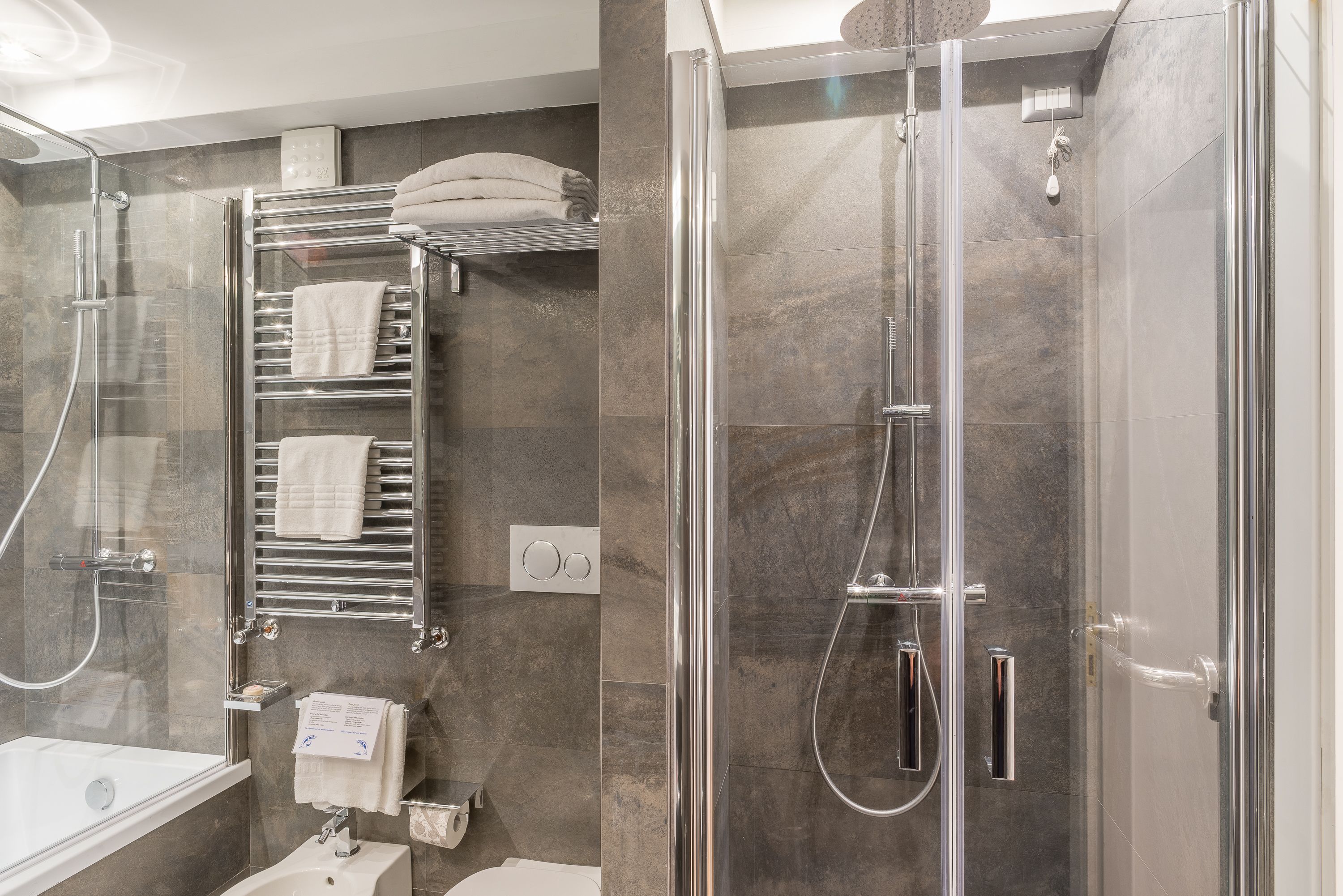 A modern bathroom with a glass-enclosed shower, a built-in towel rack, and a separate bathtub.
