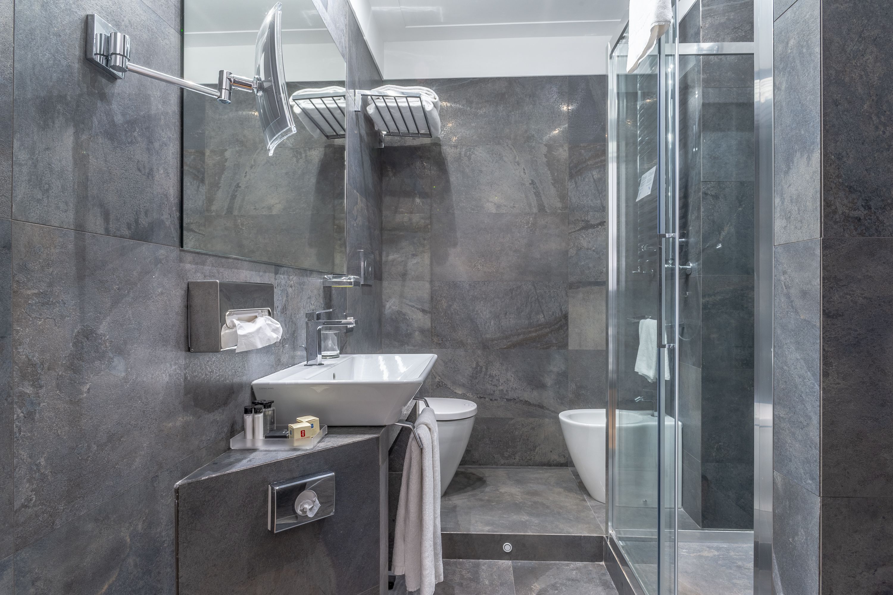 Un bany modern amb una cabina de dutxa de vidre, un lavabo blanc i un vàter.