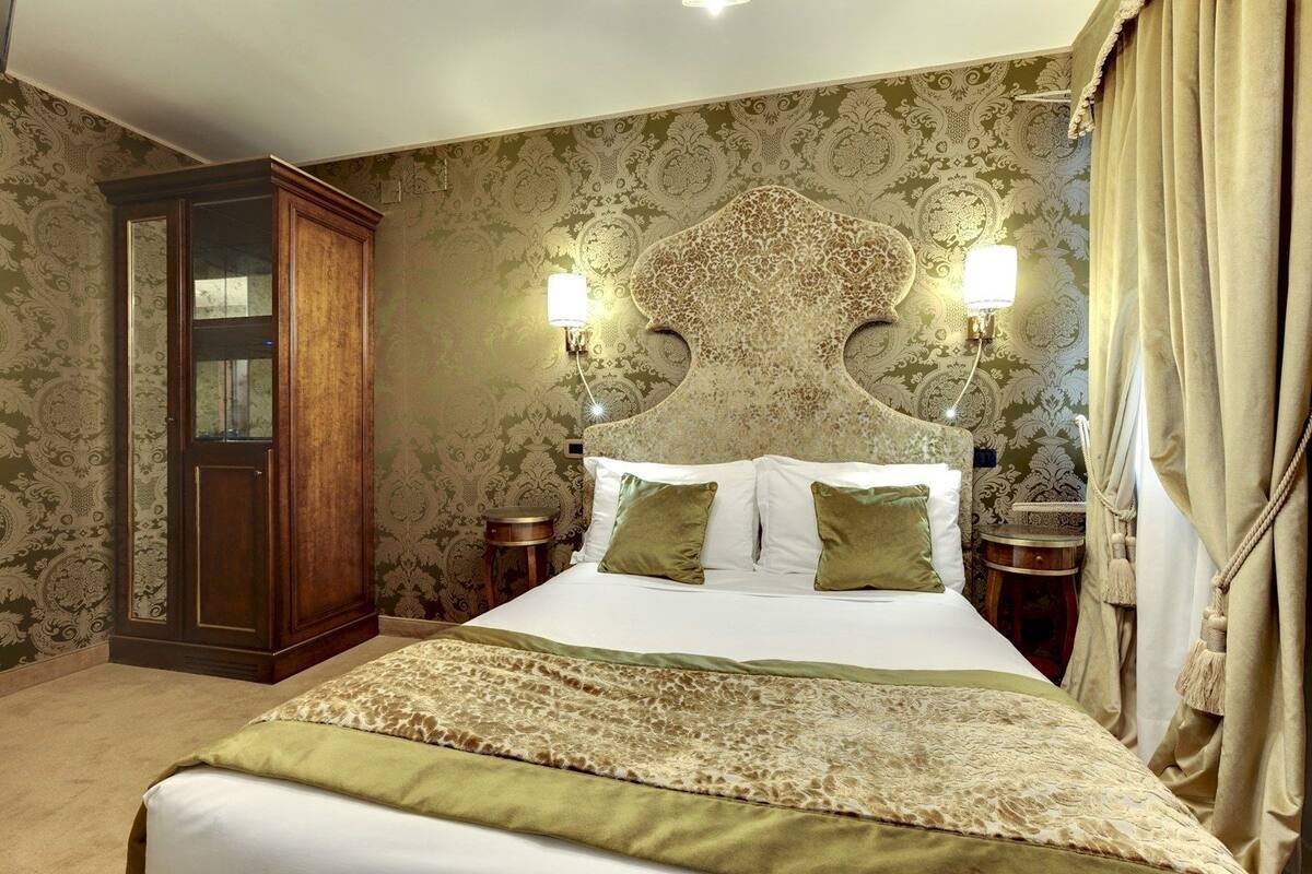 Un dormitorio con una cama grande, dos mesitas de noche, un armario y un papel tapiz estampado.