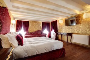 A hotel room with a large bed, a sofa, a TV mounted on the wall, and a radiator. - Hotel Casanova Venezia (Venice)