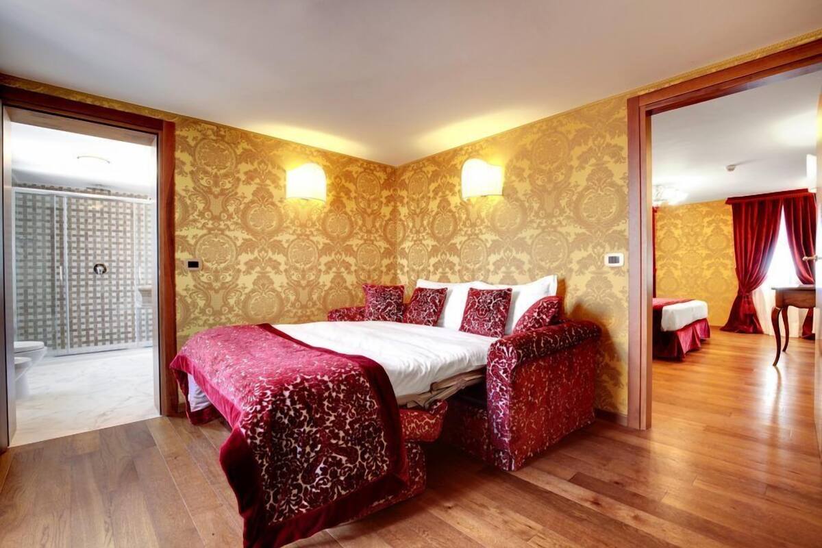 Un dormitorio con una cama grande, dos lámparas fijadas a la pared y suelo de madera.