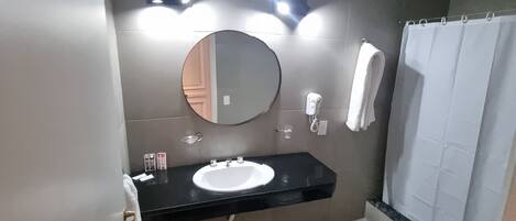 Un baño con lavamanos, espejo, toallero y retrete.
