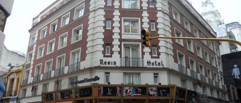 A corner building with "Resis Hotel" signage, featuring a traditional architectural style with multiple windows and balconies.
