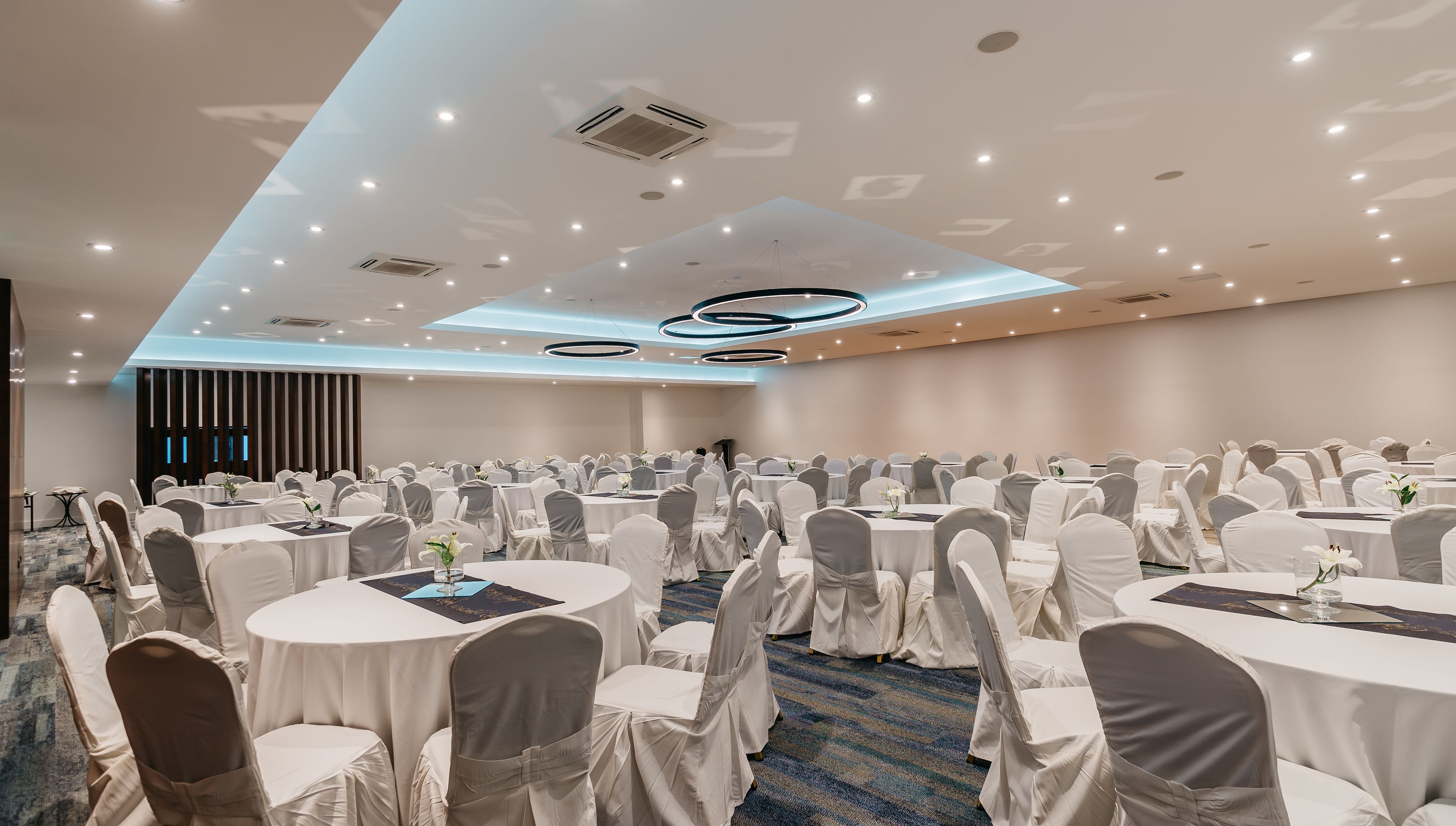 A large conference room with round tables, white chairs, and a podium.