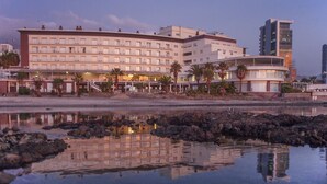 Un hotel con varios pisos, zona de piscina y vista a la playa.