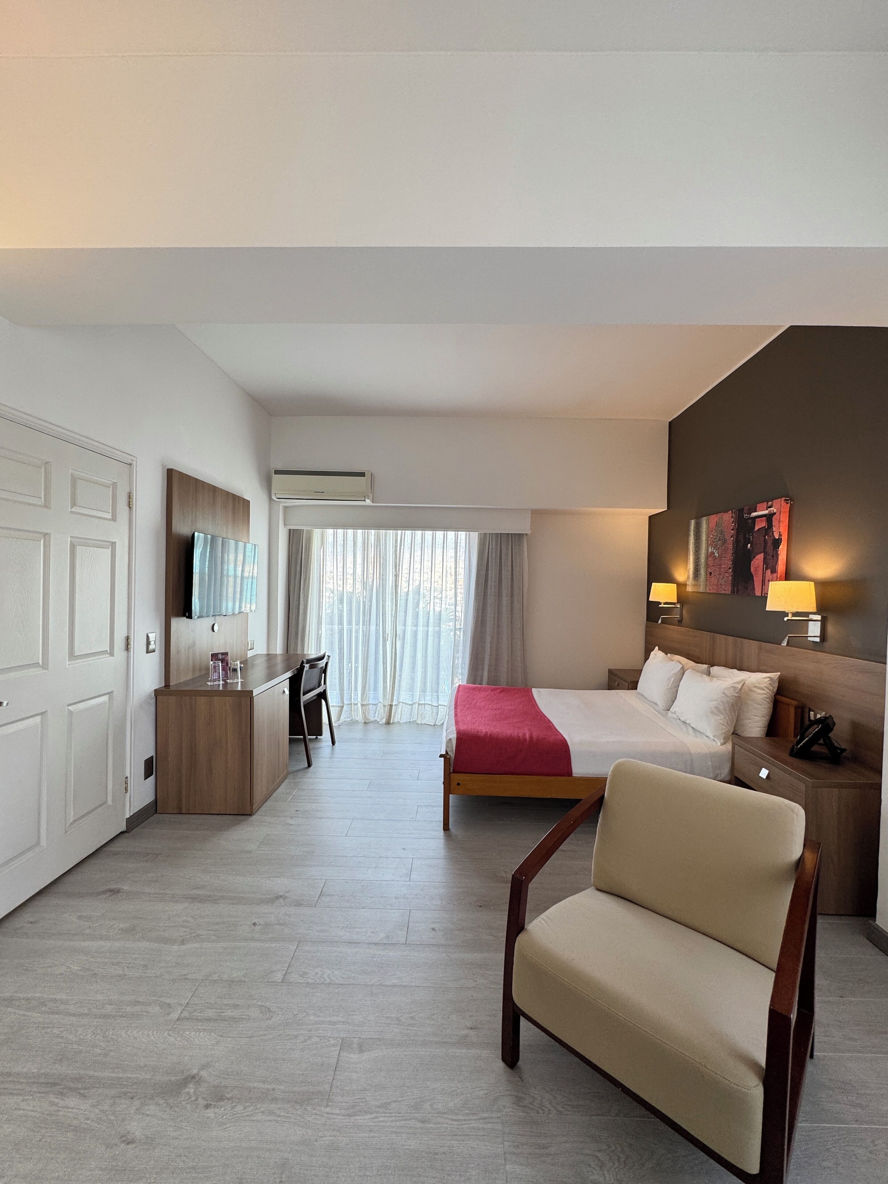 Ein Hotelzimmer mit Bett, Schreibtisch, Stuhl und Nachttisch.