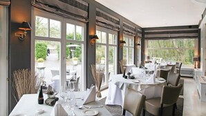 A restaurant with large windows, white tablecloths, and candle centerpieces. - Hotel Lafarques (Pepinster)