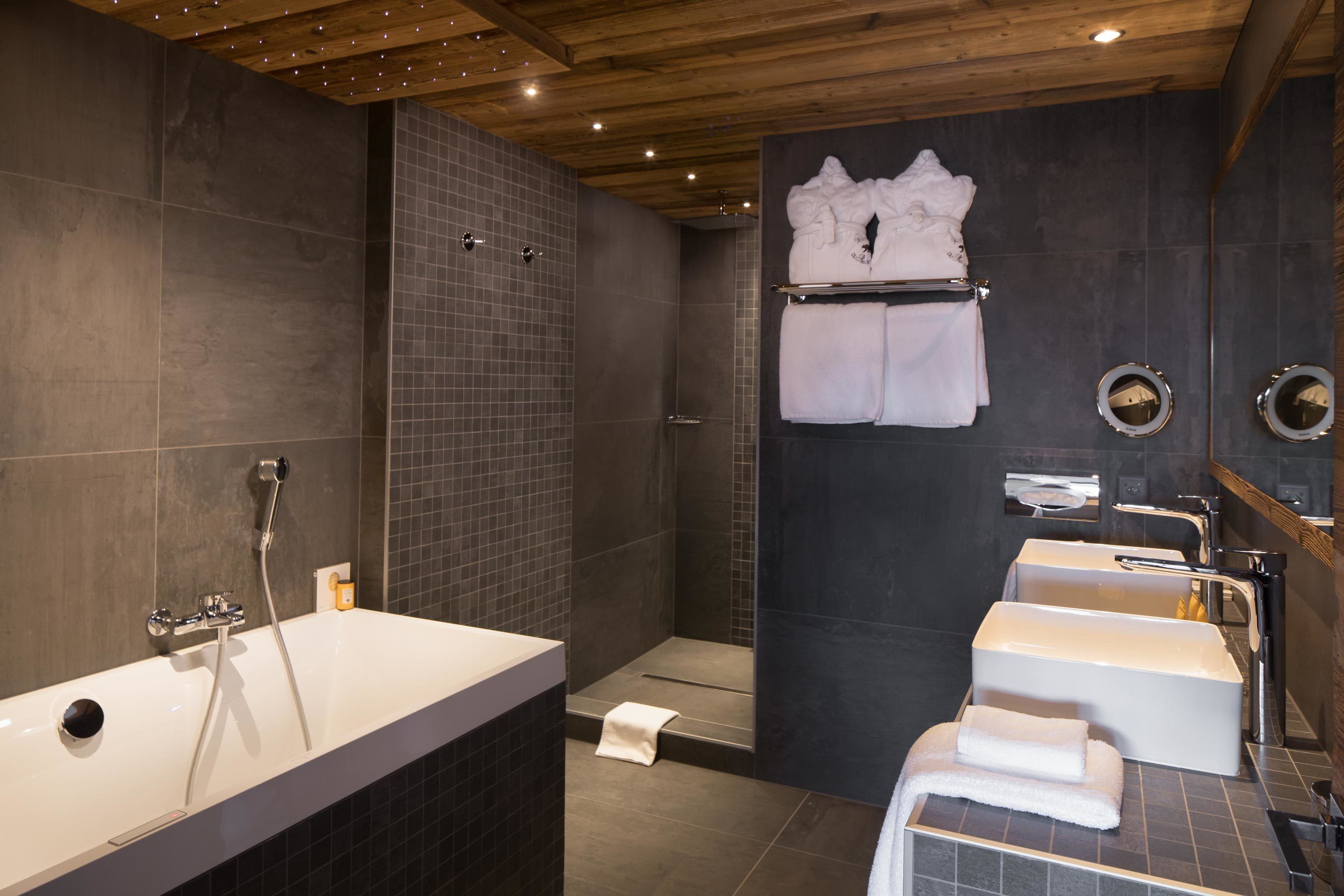Un baño moderno con una bañera grande, zona de ducha y doble lavabo.