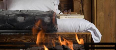 A bed with a white pillow and a gray blanket, a book titled 'Jean Cocteau Poems', and a pair of glasses on the bedside table.