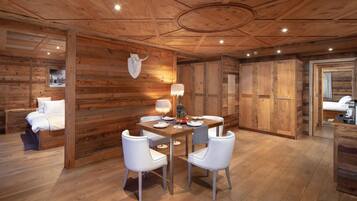 A wooden interior with a dining table, white chairs, a lamp, and a cow skull decoration.