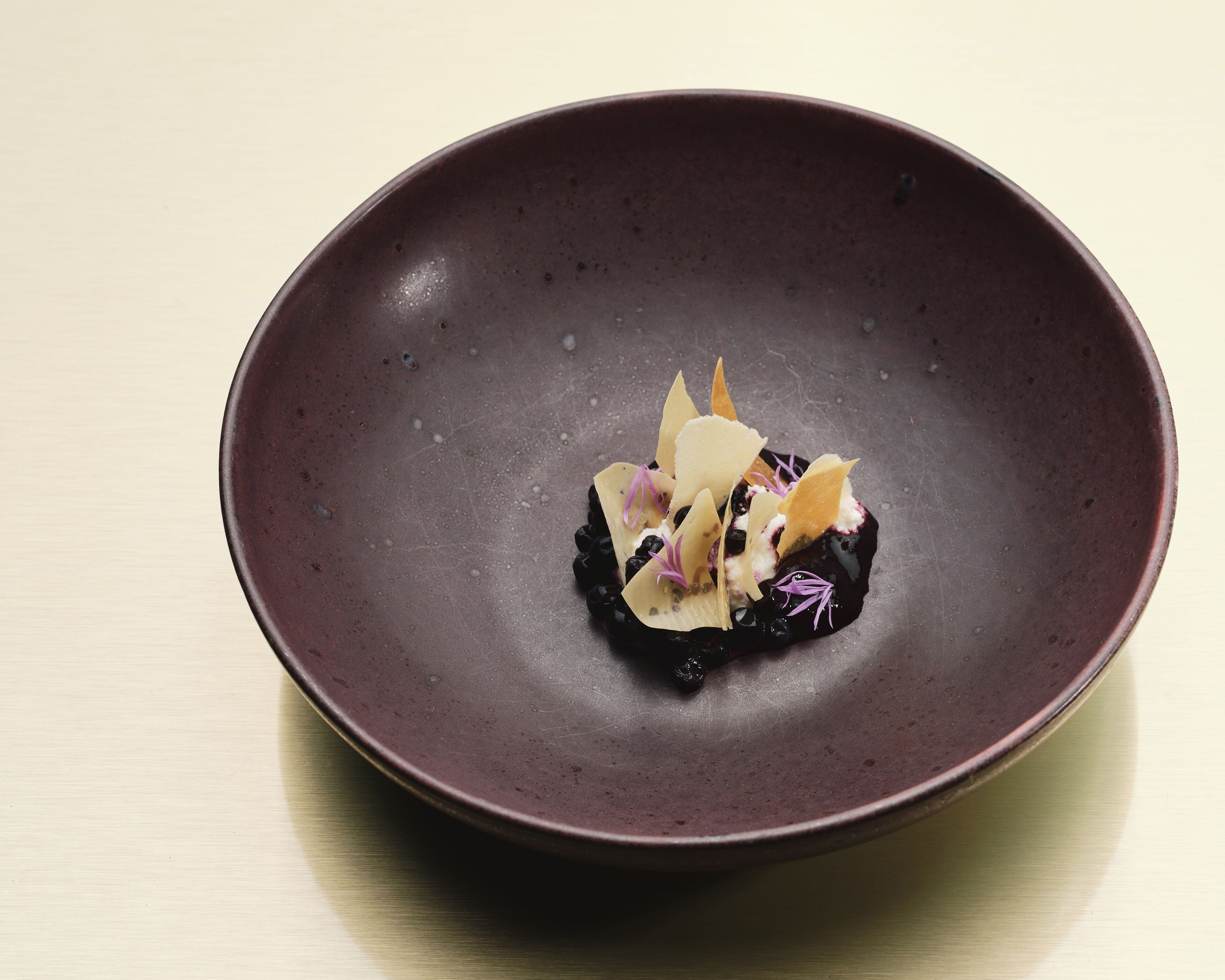 A dark ceramic plate with a dessert on a light wooden table.