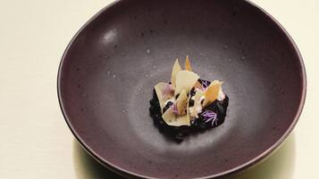 A dark ceramic plate with a dessert on a light wooden table.
