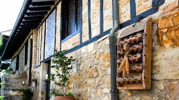 A stone building with a tiled roof and a large wooden barrel on the ground.