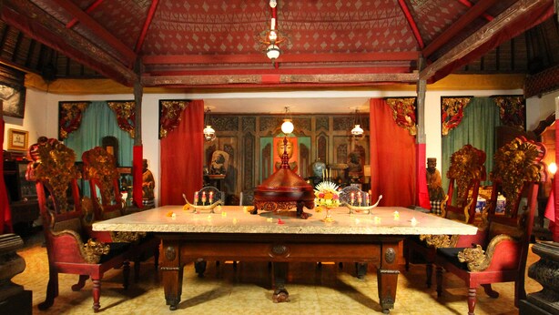 A traditional room with a large ornate table, red curtains, and a patterned ceiling. - Hotel Tugu Bali Canggu (Canggu)