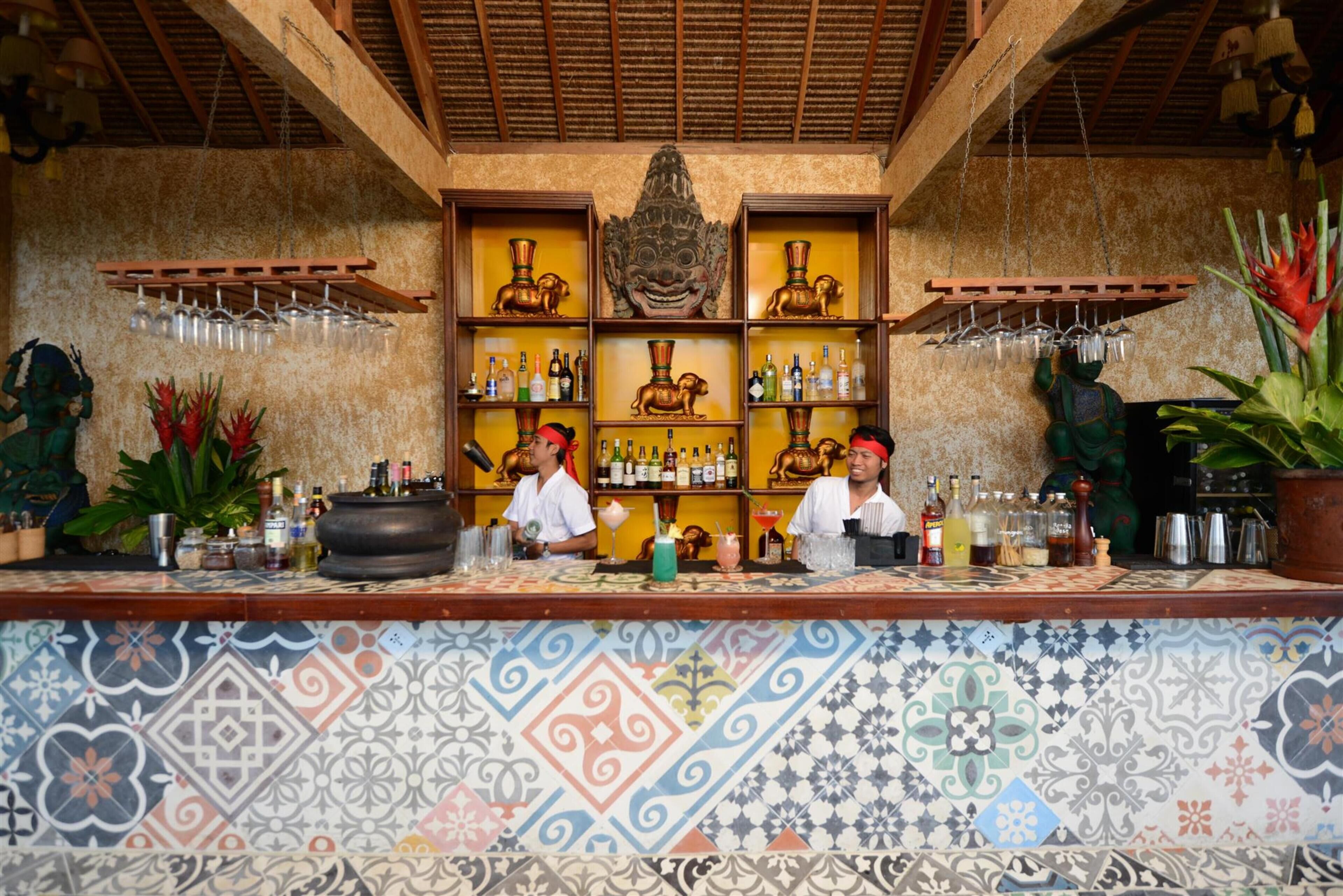 Una zona de bar con piso de baldosas, estantes con botellas y objetos decorativos.
