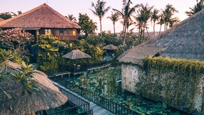 A resort with overwater bungalows, a wooden walkway, and a water garden. - Hotel Tugu Bali Canggu (Canggu)