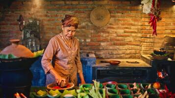 A person preparing food in a kitchen with brick walls, a traditional stove, and various cooking utensils and ingredients.