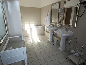 Un baño moderno con dos lavamanos, una bañera y un tocador con espejo.