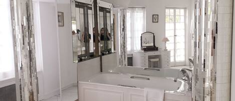 A modern bathroom with a large mirror, a bathtub, and a vanity with a sink.