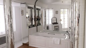 Une salle de bain moderne avec un grand miroir, une baignoire et un meuble-lavabo.