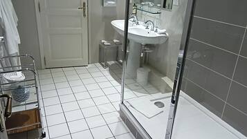 A bathroom with a glass shower enclosure, a sink, and a toilet.
