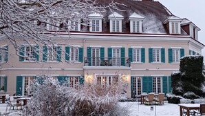 Un bâtiment à deux étages doté d’un balcon, entouré d’un paysage enneigé et offrant des places assises à l’extérieur.
