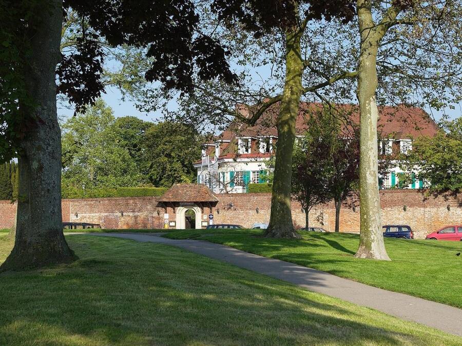 A historic building with a brick wall, a pathway, and trees.