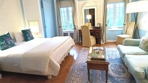 Une chambre d’hôtel avec un grand lit, un bureau, une chaise, un canapé et une petite table.