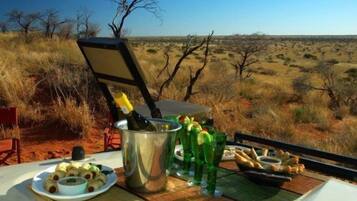 A dining setup with a view of a savannah landscape.