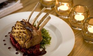 A plate with a grilled lamb chop, a red sauce, and green garnish. - The Motse - Tswalu Kalahari Luxury Private Game Reserve (Kuruman)