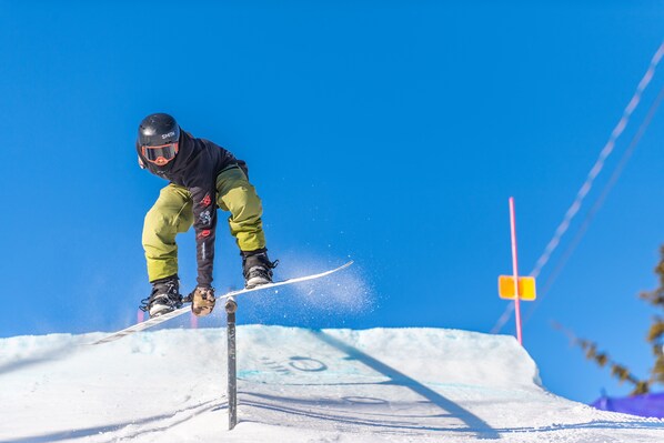 Un snowboarder realizando un salto sobre un riel.