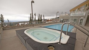 A swimming pool with a view of a mountain and a building labeled "The Blaney Stone Irish Tavern". - Inn at Big White (Beaverdell)
