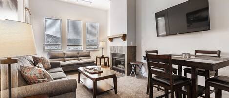 Un salón espacioso con chimenea, zona de comedor y un televisor grande montado en la pared.