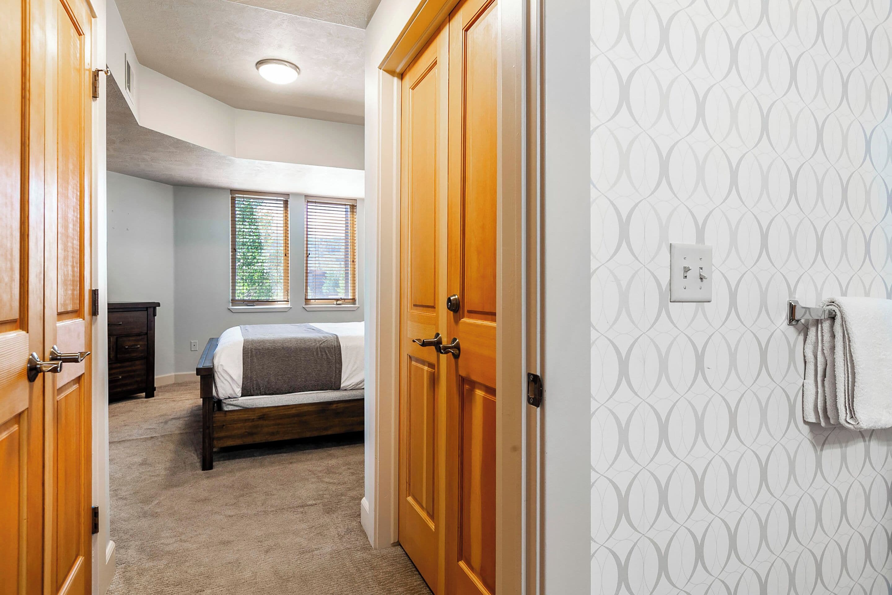 A bedroom with a bed, wooden wardrobe, and a window with blinds.