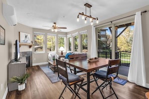 A spacious room with a wooden dining table, chairs, a ceiling fan, and large windows offering a view of the outdoors. - Crestview Condominiums by All Seasons Resort Lodging (Park City)