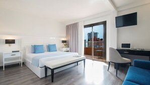 Een moderne hotelkamer met een groot bed, een bureau, een stoel en een balkon met uitzicht over de stad.
