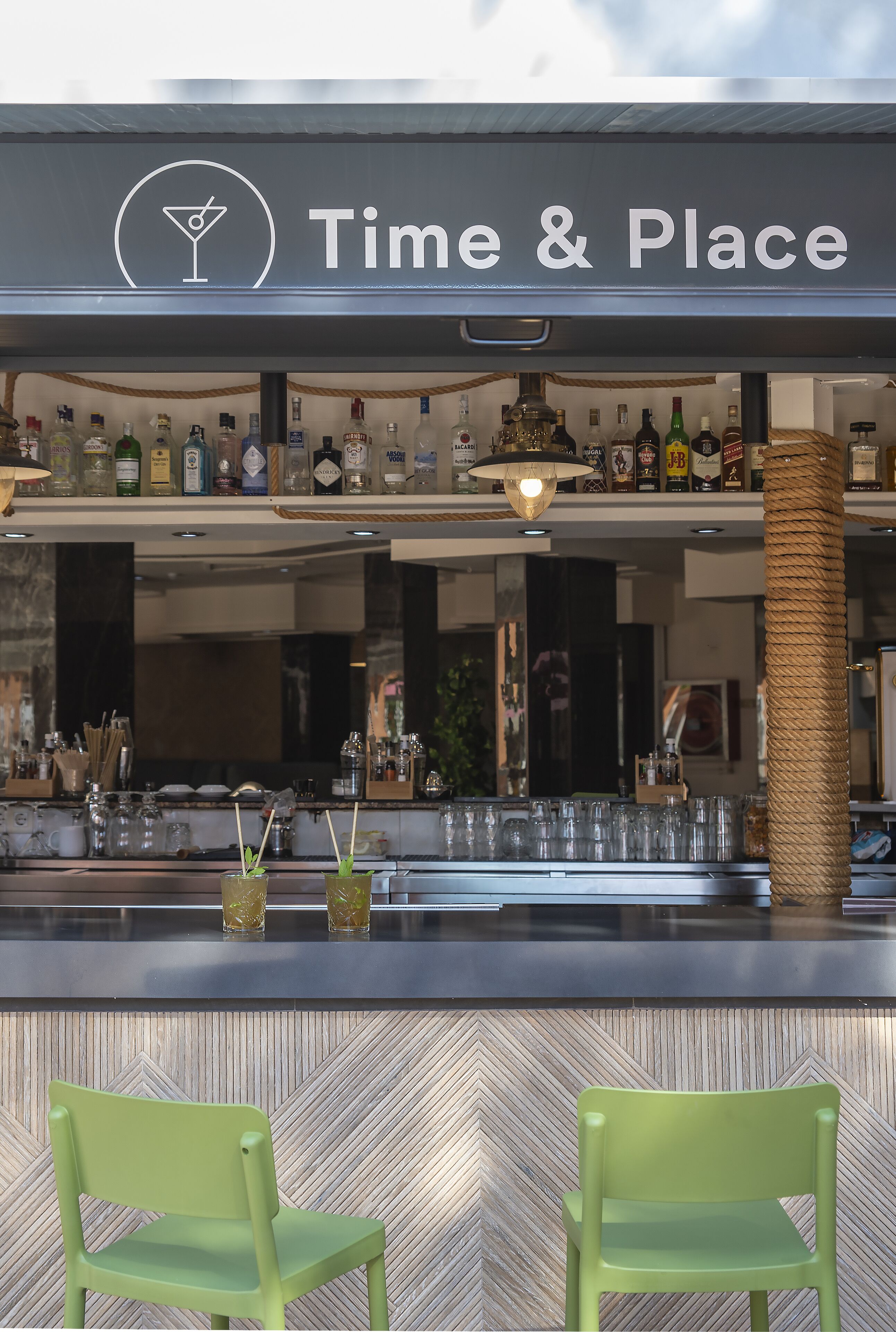 A bar area with a sign reading "Time & Place" and a variety of bottles and glasses on shelves.