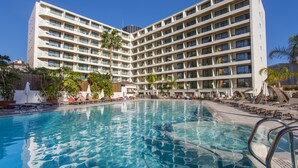 Un hotel con un'ampia area piscina, numerosi balconi e un design architettonico moderno.