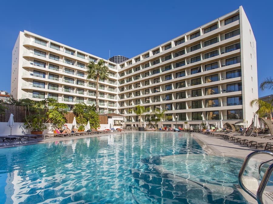 Un hotel con un amplio espacio de piscina, varios balcones y un diseño arquitectónico moderno.