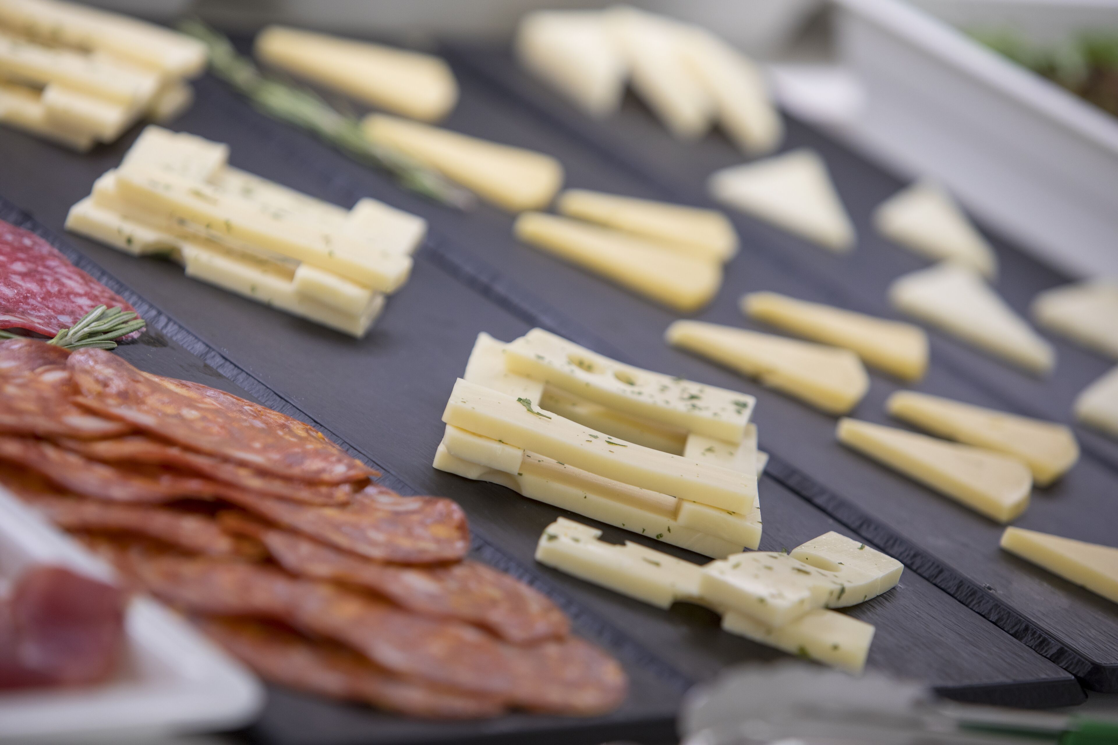 A variety of cheeses and cured meats on a slate board.