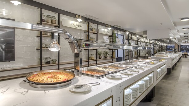 Un'area buffet con sezioni segnalate per carni e verdure, una grande teglia da portata e una varietà di piatti.