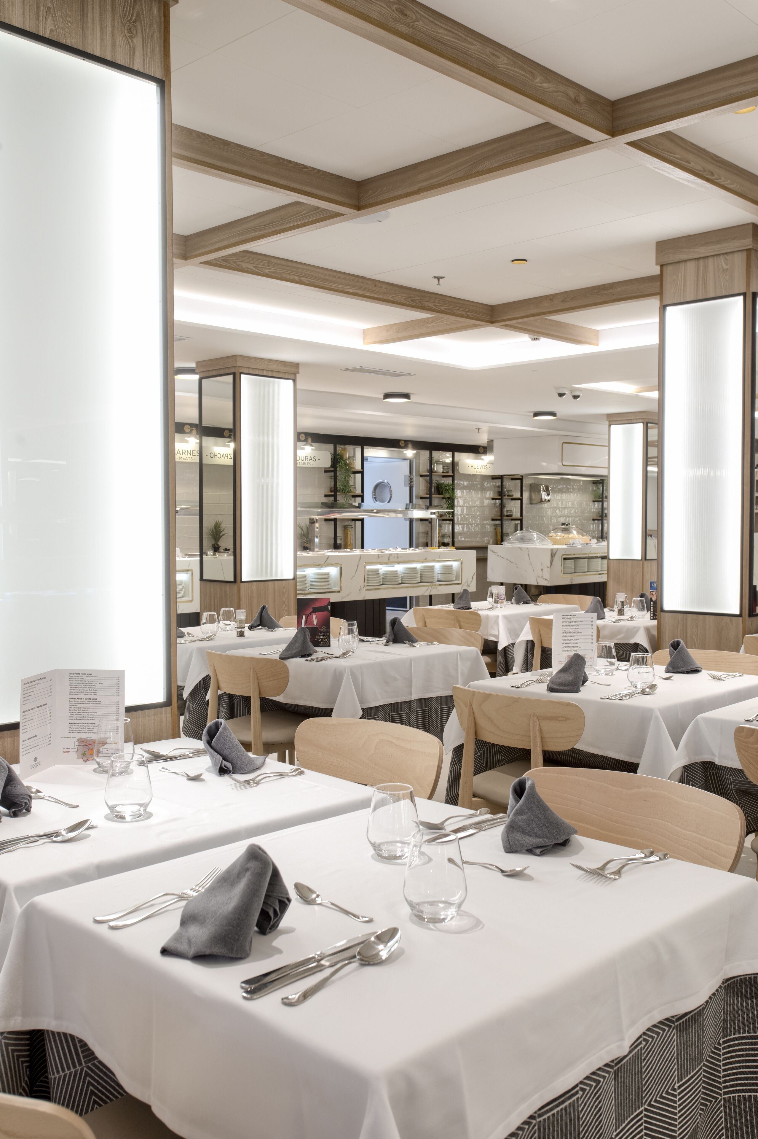 A restaurant with multiple tables set for dining, featuring white tablecloths and neatly arranged cutlery.