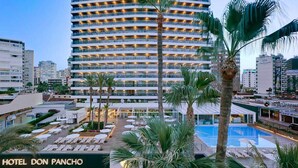 A multi-story hotel with a pool area, palm trees, and a clear sky. - Don Pancho (Benidorm)