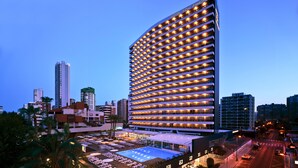 A high-rise hotel with a curved facade, multiple balconies, and a rooftop pool area. - Don Pancho (Benidorm)