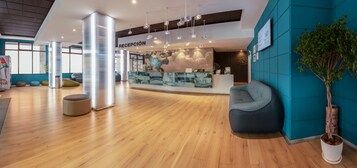 A modern reception area with a wooden floor, teal walls, and a reception desk.