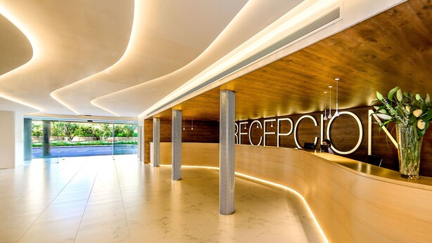 A modern reception area with a marble floor, a reception desk, and a large reception sign. - Hotel Carlos l (Benidorm)